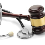 Close up of stethoscope and gavel on white background